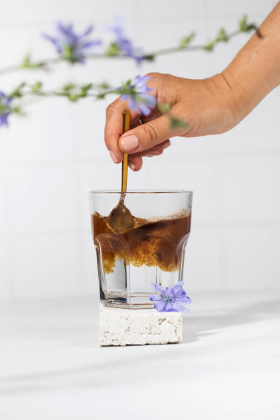 istock A woman's hand will pour granulated chicory powder into a white mug. Drink chicory. 1334776861