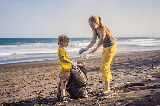 Mother and son are cleaning up the beach. Natural education of children.