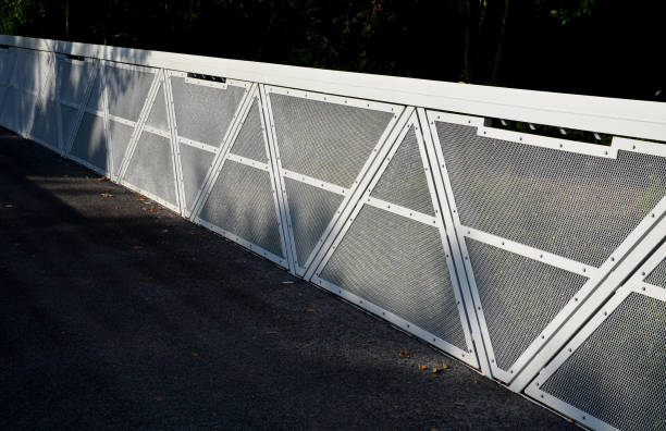 istock path for cyclists with an asphalt surface. galvanized iron railing over road barriers. Bridge railing with tilting to the sides. railing made of perforated sheet metal in the shape of a triangle 1334781315