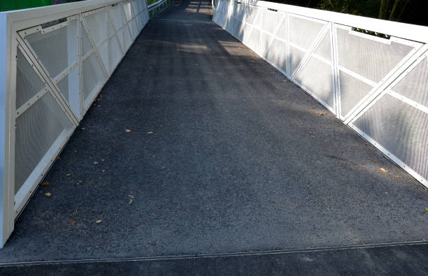 istock path for cyclists with an asphalt surface. galvanized iron railing over road barriers. Bridge railing with tilting to the sides. railing made of perforated sheet metal in the shape of a triangle 1334781366