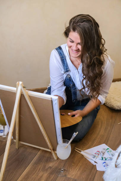 istock Creative painter in working process. Artist workplace, hobby, craft tools. Artist female canvas painting. Professional young woman painter draws in the workshop 1334784247