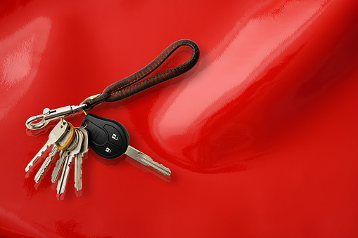Bunch of Keys with leather key ring isolated on on shiny red vinyl background with copy space.