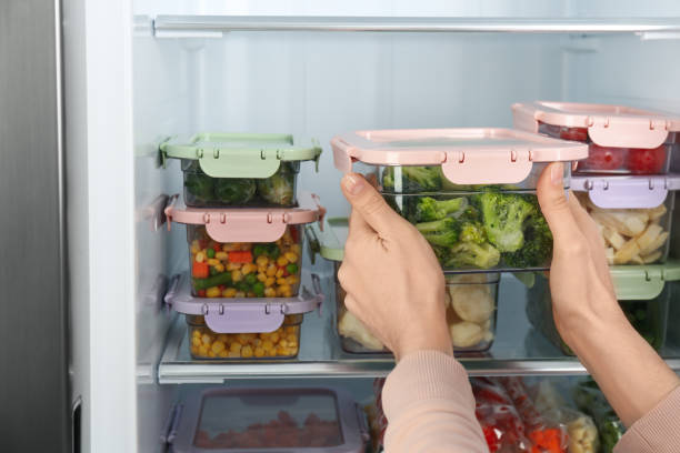 istock Woman taking container with frozen broccoli from refrigerator, closeup 1334791934