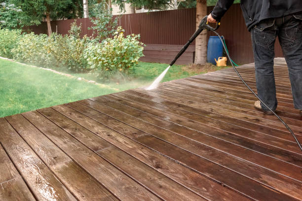 Man cleaning walls and floor with high pressure power washer. Washing terrace wood planks and cladding walls. stock photo