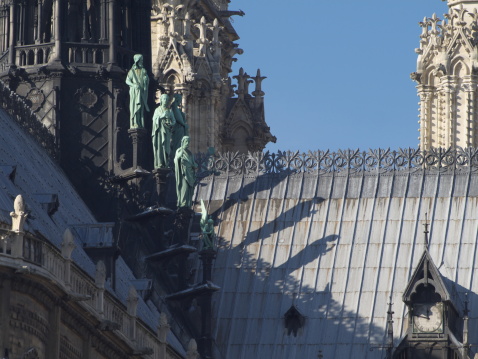 At the base of the spire of the cathedral, the Northeast, three of the twelve apostles with their shadow on the roof.