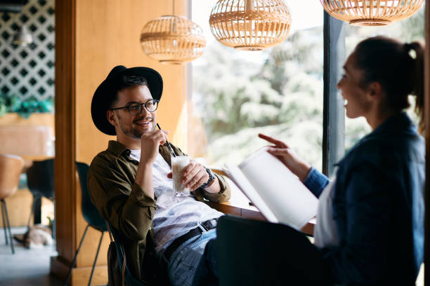 istock Young student drinking coffee while learning with female friend in a cafe. 1334800333