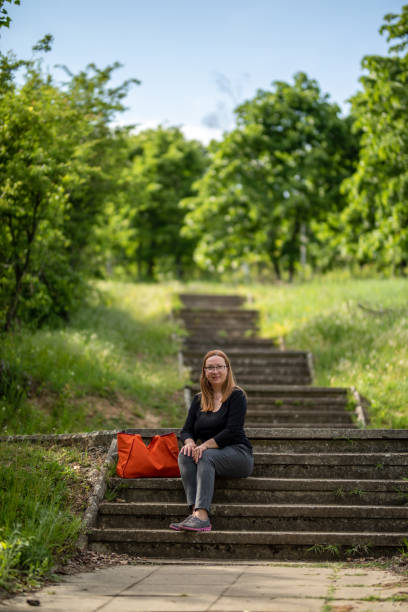 istock Smiling attractive woman sitting outdoors on the stairs 1334800362