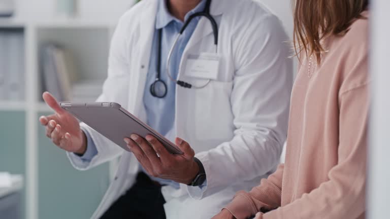 4k video footage of young doctor using a digital tablet with a patient in an office