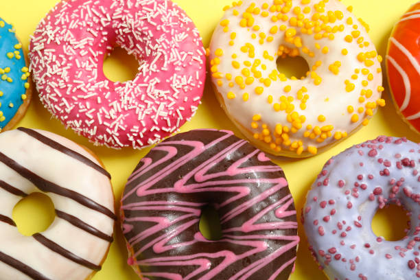 istock Delicious glazed donuts on yellow background, flat lay 1334802645