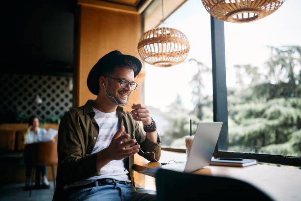 istock Young happy man making video call via laptop while studying in cafe. 1334802713