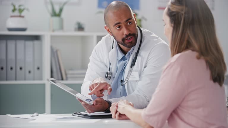 4k video footage of a young male doctor going through paperwork with a patient in an office