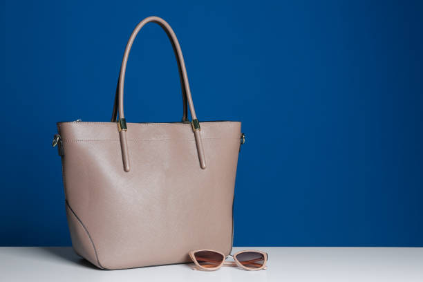 istock Stylish woman's bag and sunglasses on white table. Space for text 1334802991