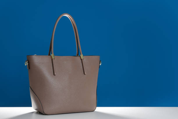 istock Stylish woman's bag on white table against blue background. Space for text 1334803137