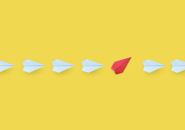 istock Business concept for new ideas creativity and innovative solution, Group of white paper plane in one direction and one blue paper plane pointing in different way on yellow background 1334804372