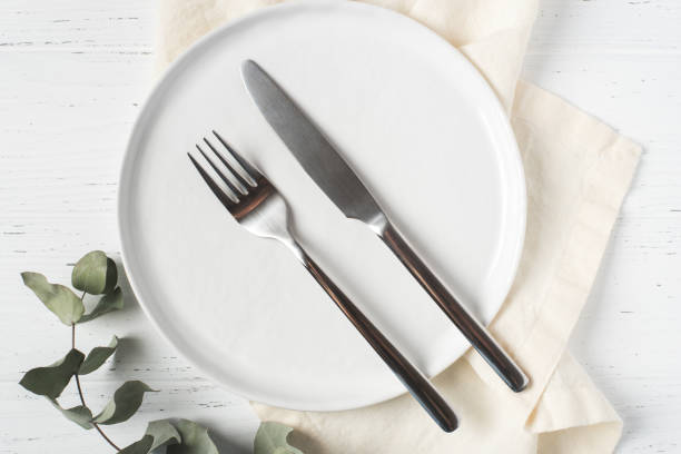 istock An empty plate and cutlery on a white table. 1334805508