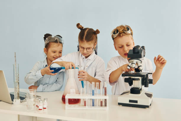 istock Test tubes with colorful liquid. Children in white coats plays a scientists in lab by using equipment 1334805672