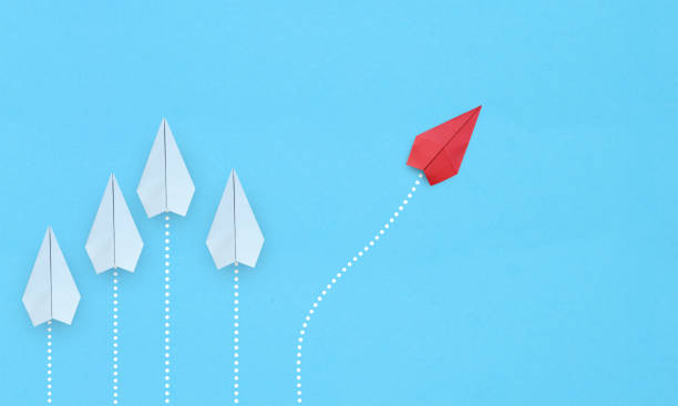 istock Group of white paper planes in one direction and one red paper plane pointing in different way on blue background. Business for new ideas creativity and innovative solution concepts 1334806366