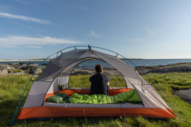 istock Young man sitting inside tent, admiring beach scenery 1334807487