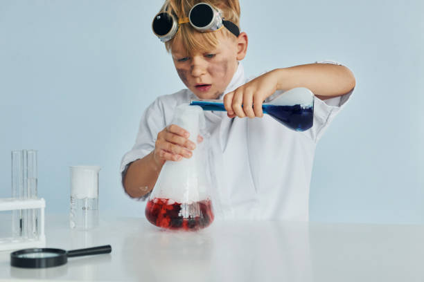 istock Little boy in coat playing a scientist in lab by using equipment 1334807871