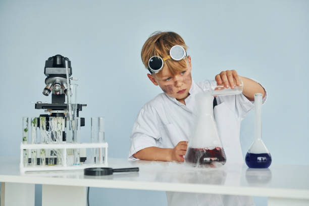 istock Little boy in coat playing a scientist in lab by using equipment 1334807888