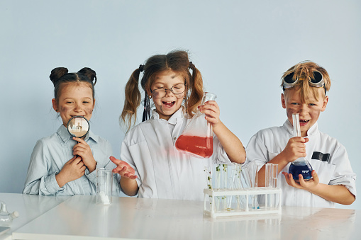 Happy friends smiling. Children in white coats plays a scientists in lab by using equipment.