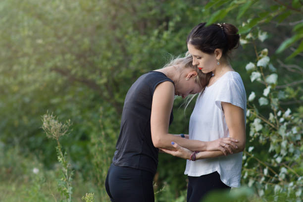 Young women hug in nature. A woman provides psychological assistance to her friend at a yoga session outdoors. The concept of meditation, spiritual practices. Copyspace Young women hug in nature. A woman provides psychological assistance to her friend at a yoga session outdoors. The concept of meditation, spiritual practices. Place for text mercy hug stock pictures, royalty-free photos & images