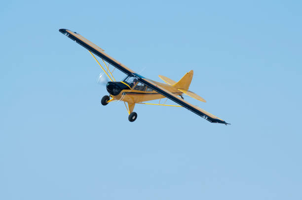 Yellow single engine light aircraft flying in the blue sky.