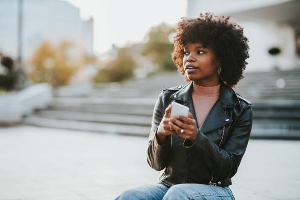 istock Smiling afro woman using phone while she is out in the city 1334810815