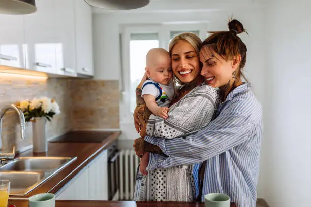 Loving lesbian couple playing with their baby while spending time together at home.