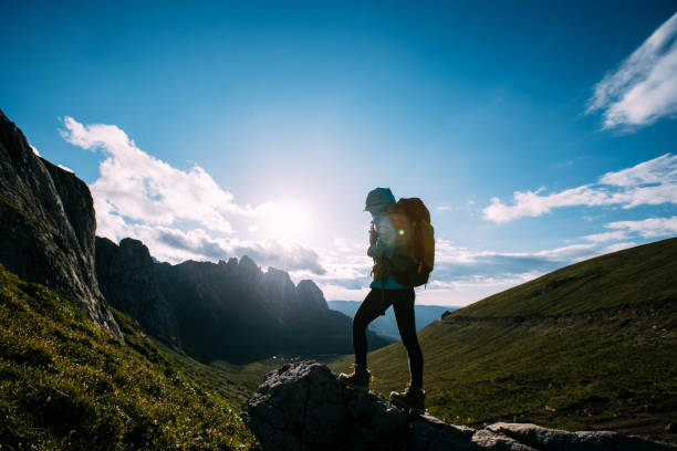 istock Successful woman backpacker hiking on sunset alpine mountain top 1334817370