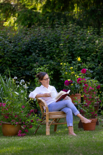 женщины любят отдыхать в саду - senior women senior adult bench flower стоковые фото и изображения