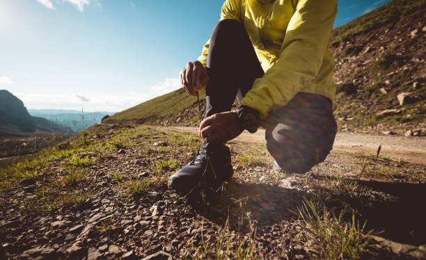 женщина-трейлраннер завязывает шнурки во время бега по пересеченной местности на вершине горы - jogging cross country running hiking outdoors стоковые фото и изображения