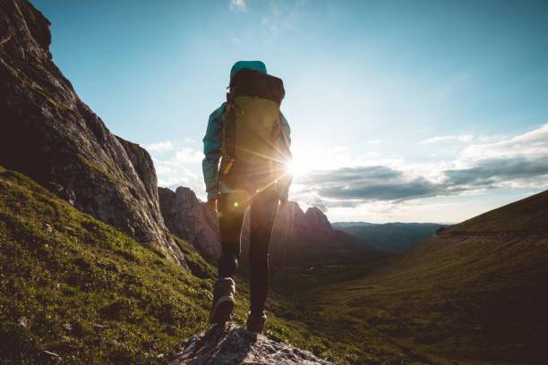 istock Successful woman backpacker hiking on sunset alpine mountain top 1334823085