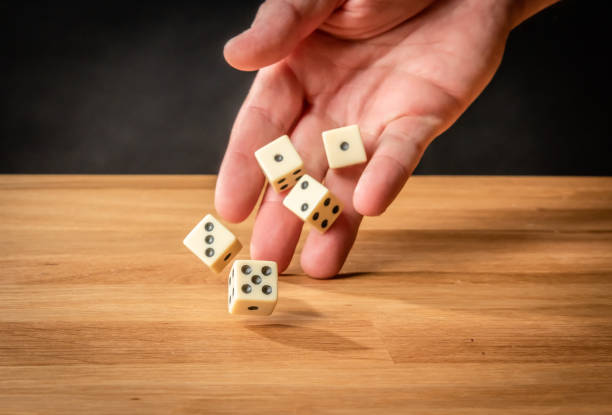 istock Hand throwing five dice on a wooden table.. 1334825259