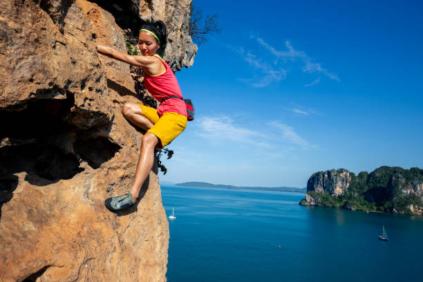 istock Young woman rock climber climbing on seaside cliff 1334825467