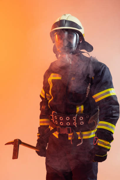 istock One uniformed firefighter posing against an orange background covered in smoke 1334826160