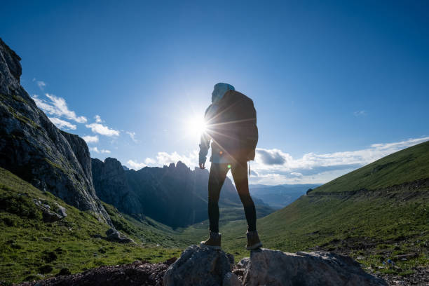istock Successful woman backpacker hiking on sunset alpine mountain peak 1334829684
