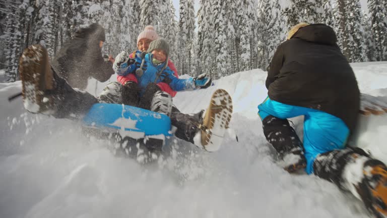 SLO MO Woman sledding down the snowy hill with her young son