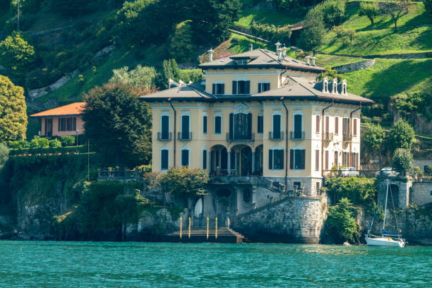 Lenno, Italy - July 1, 2013: A man driving a small boat in front of  the Villa Balbianello on Lake Como.  The villa was built in the 1500's and is located on the tip of a small peninsula on the western shore of the lake.