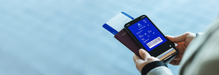 Closeup of a woman with electronic boarding pass on phone with passport and flight ticket at airport. Digital airplane ticket on the smartphone mobile app.