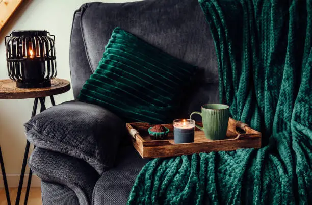 Photo of Modern autumn hygge set in living room. Dark green interior elements.