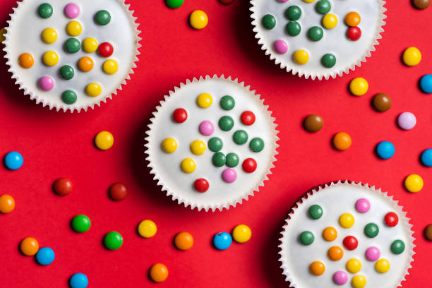 muffins doces de cacau com chocolate branco e bombons coloridos - cupcake chocolate icing candy - fotografias e filmes do acervo
