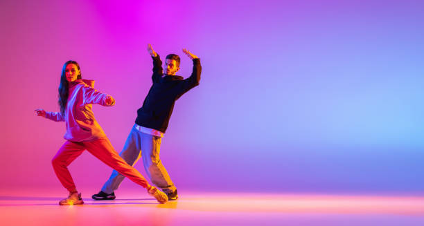 Flyer. Two young people, guy and girl dancing contemporary dance, hip-hop over pink background in neon light. Smooth movements. Two young people, guy and girl, dancing contemporary dance over pink background in neon light. Modern dance aesthetics concept contemporary dance stock pictures, royalty-free photos & images