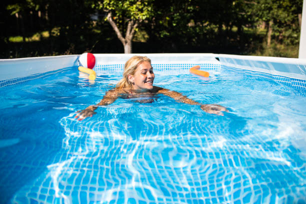 A happy young woman swimming in an above-ground pool stock photo