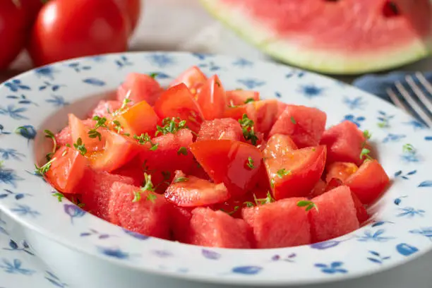 Delicious summer salad with fresh and ripe tomatoes and watermelon served on a plate. Closeup view