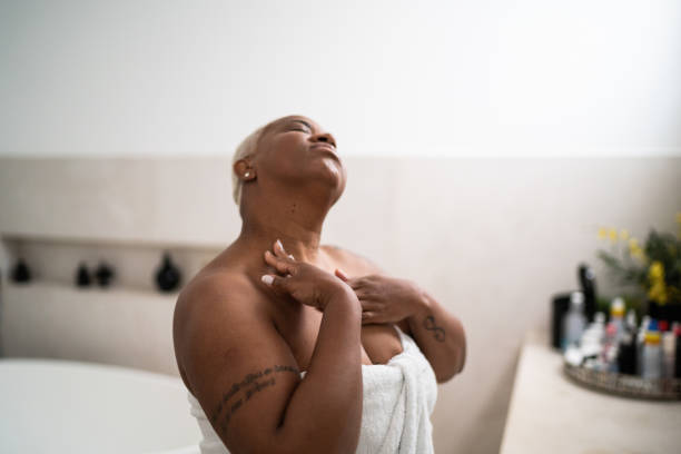 Woman applying body mosture in the bathroom at home Woman applying body mosture in the bathroom at home semi dress stock pictures, royalty-free photos & images