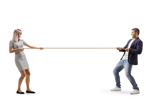 Full length profile shot of a young man and woman pulling a rope isolated on white background