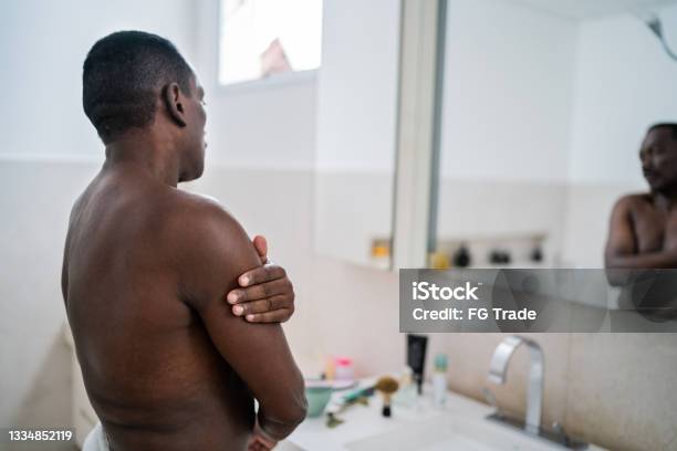Senior man applying moisture on body at home