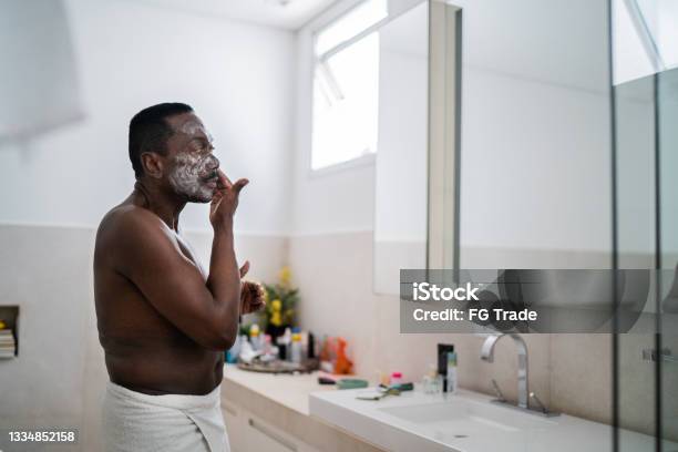 Senior man applying facial mask at home