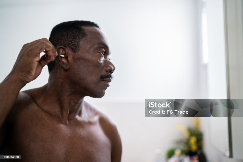 Senior man cleaning his ear with a cotton swab at home African-American Ethnicity Stock Photo